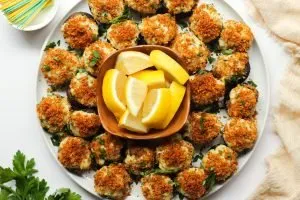 Stuffed mushrooms with crab on a white plate, with toasted brown breadcrumbs on top.