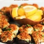 Close up of stuffed mushrooms with crab on a white plate - pinterest pin.